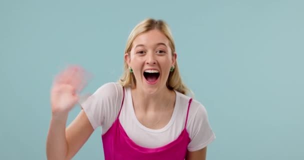 Hand, hello and face of happy woman in studio wave, calling and excited greeting on blue background. Portrait, smile and female model with palm emoji for attention, hey or bye, come or waving sign. - Footage, Video