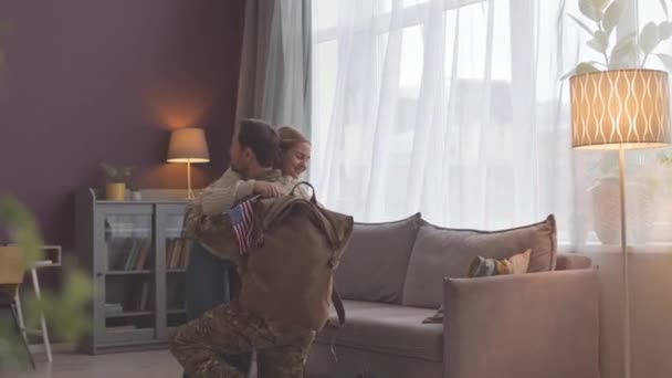 Felice ragazza caucasica con la bandiera degli Stati Uniti in mano abbracciando padre tanto atteso è tornato a casa dal servizio militare - Filmati, video
