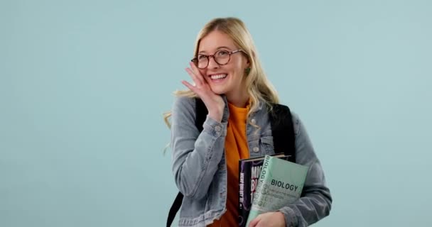 Mujer, estudiante y nerd en gafas con libros, ciencia y sonrisa en retrato con aprendizaje sobre fondo azul. Emocionado, feliz y educativo, conocimiento en la universidad con libro de texto y estudio en estudio. - Metraje, vídeo