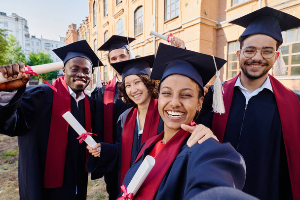 Gruppo di studenti laureati felici fare selfie ritratto contro la loro università - Foto, immagini