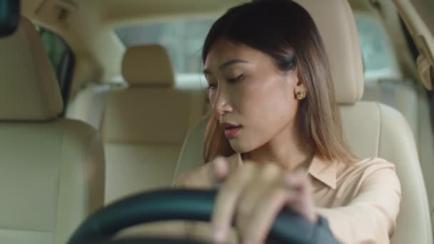 Üzgün görünümlü Asyalı iş kadını gözlüğünü çıkarıyor, burun köprüsünü çimdikliyor ve sonra araba koltuğuna yaslanıyor. - Video, Çekim