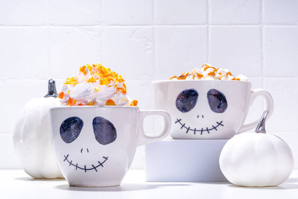 Hauskoja lapsia kaakaota tai kahvi latte vaahtokarkkia ja kermavaahtoa, koristeltu pelottava Jack kasvot muki. Halloween puolue ruoka ja juoma kopioi tilaa - Valokuva, kuva