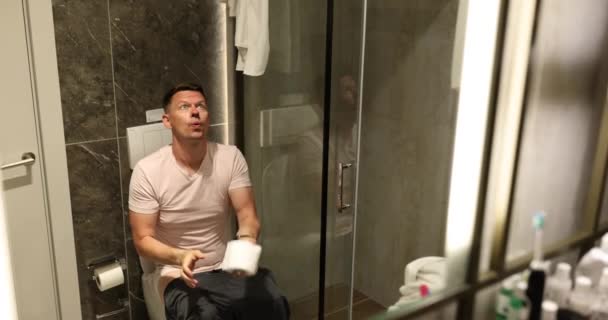 Człowiek cierpiący na hemoroidy wyrzuca papier toaletowy do toalety. Problemy z trawieniem - Materiał filmowy, wideo