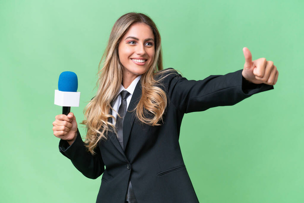 Young pretty Uruguayan tv presenter over isolated background giving a thumbs up gesture - Photo, Image
