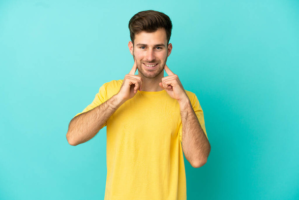 Young caucasian handsome man isolated on blue background smiling with a happy and pleasant expression - Photo, Image