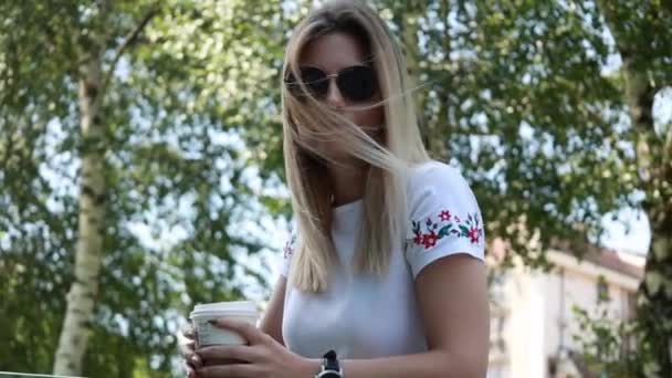 vrouw in casual kleding met een kopje koffie naar buiten te gaan - Video