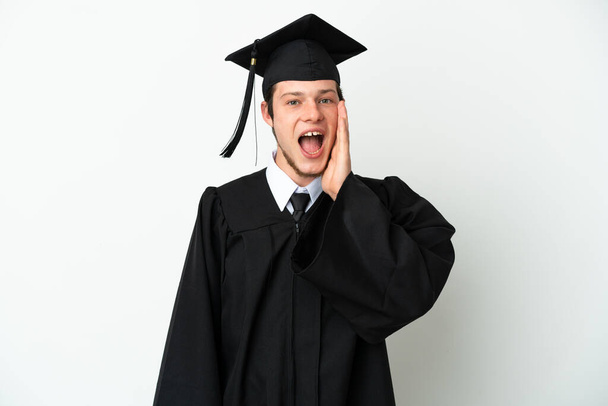 Graduado universitario joven aislado sobre fondo blanco con sorpresa y expresión facial impactada - Foto, imagen