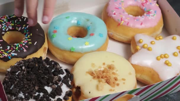 someones hand picks a donut from a box of sweet delicious variety of donuts - Footage, Video
