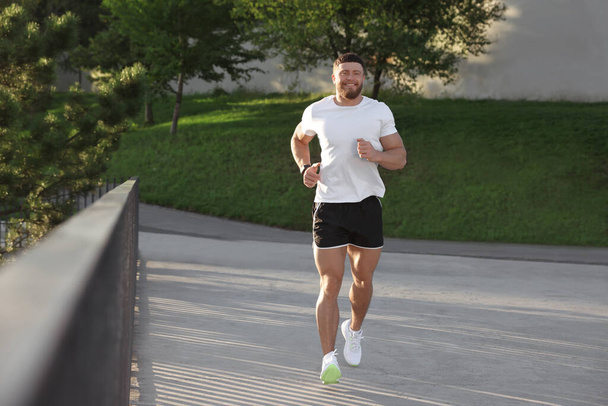 Smiling man running outdoors on sunny day - Foto, Imagem