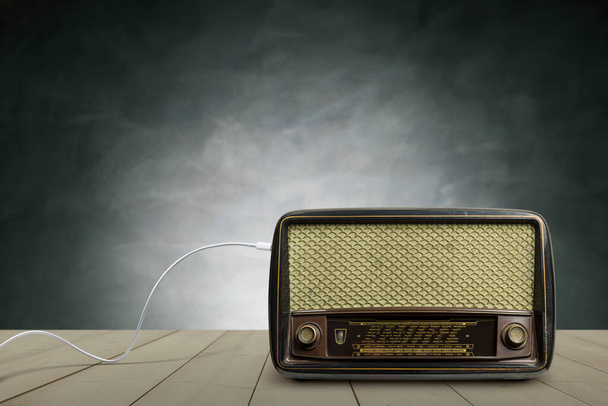 Antique radio on wooden table with concrete wall background. - Photo, Image
