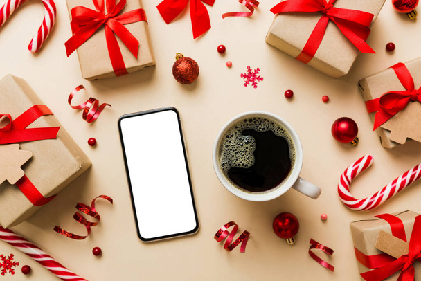 κορυφαία άποψη του έξυπνου τηλεφώνου με ζεστό φλιτζάνι καφέ. Χριστουγεννιάτικη διακόσμηση σε χρωματιστό φόντο. - Φωτογραφία, εικόνα