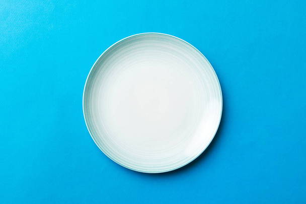 Вид сверху на изолированный цветной фон пустой круглой голубой тарелки для еды. Пустое блюдо с местом для дизайна. - Фото, изображение