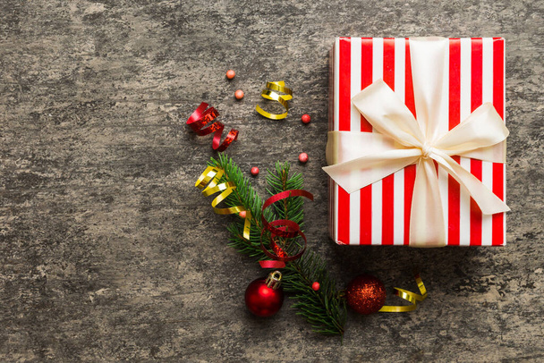 Зверху - різдвяні прикраси і коробка з подарунками на кольоровому фоні з копіювальним простором. Різдво або з новорічною композицією. - Фото, зображення