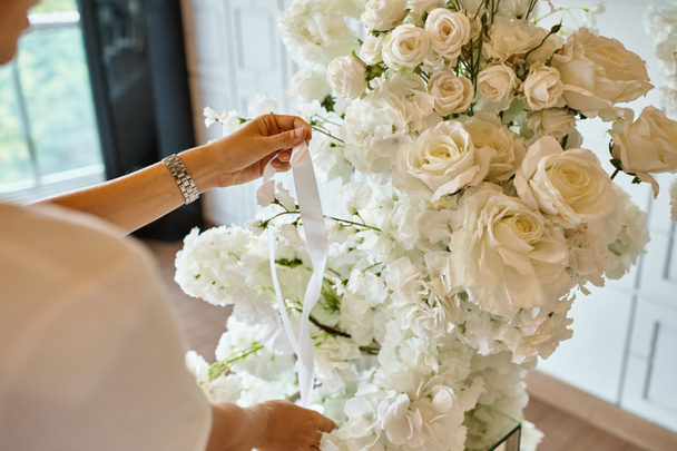 обрізаний вид на флориста зі стрічкою біля білої квіткової композиції в залі подій, прикраса бенкету - Фото, зображення