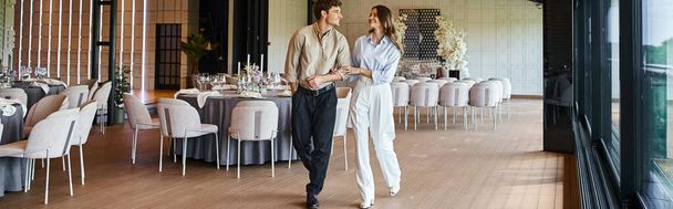 ευτυχισμένο ζευγάρι περπάτημα κατά μήκος του χώρου του γάμου με διακοσμημένα τραπέζια, ειδική προετοιμασία ημέρα, πανό - Φωτογραφία, εικόνα