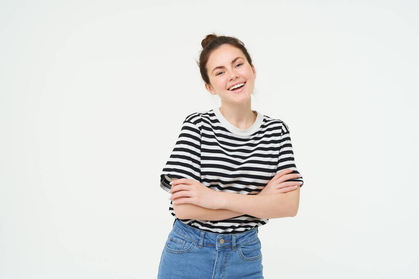 Εικόνα χαρισματικής νεαρής γυναίκας με ριγέ t-shirt και τζιν, που δείχνει σίγουρη και χαρούμενη, χαμογελαστή στην κάμερα, ειλικρινή συναισθήματα, λευκό φόντο. - Φωτογραφία, εικόνα
