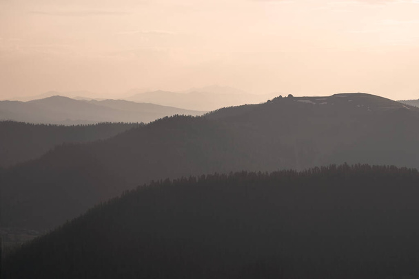 Χρυσό ηλιοβασίλεμα στο ορεινό τοπίο. Στρώματα από φόντο βουνών. Η σιλουέτα των βραδινών βουνών στο ηλιοβασίλεμα. - Φωτογραφία, εικόνα