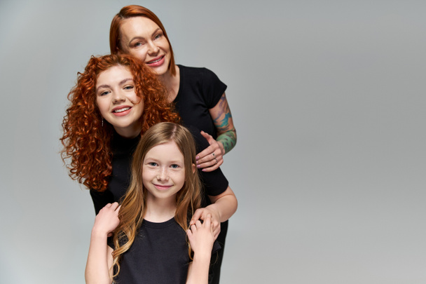 generations concept, delightful family with red hair posing in matching attire on grey background - Foto, afbeelding