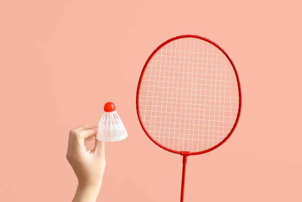 Female hand holding shuttlecock and badminton racket on pink background - Photo, Image