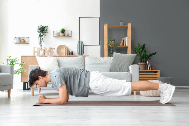 Handsome young man in plank position at home - Photo, Image