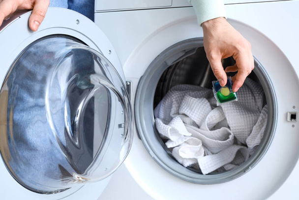 Junger Mann steckt Wäschekapsel in Waschmaschine, Nahaufnahme - Foto, Bild
