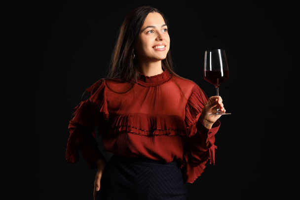 Mujer joven con copa de vino sobre fondo negro - Foto, Imagen