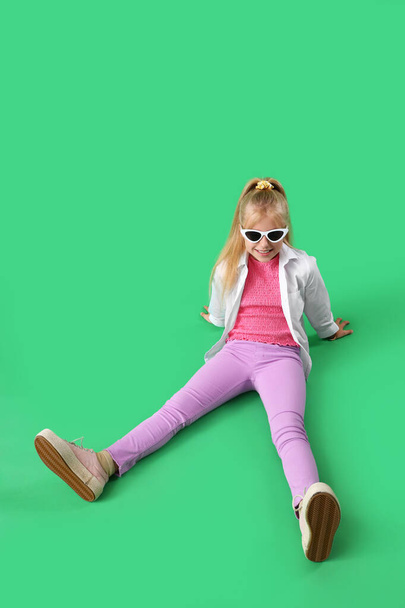 Κομψό κοριτσάκι κάθεται σε πράσινο φόντο - Φωτογραφία, εικόνα