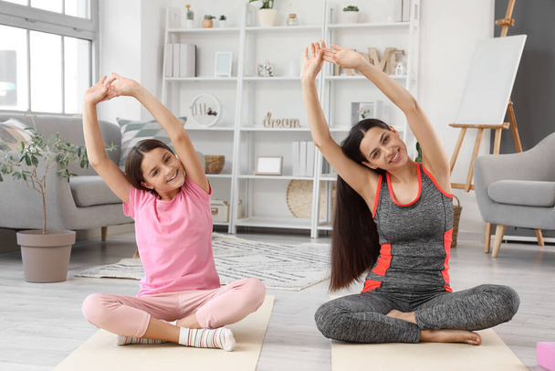 Deportiva madre con su hija pequeña entrenando en casa - Foto, imagen
