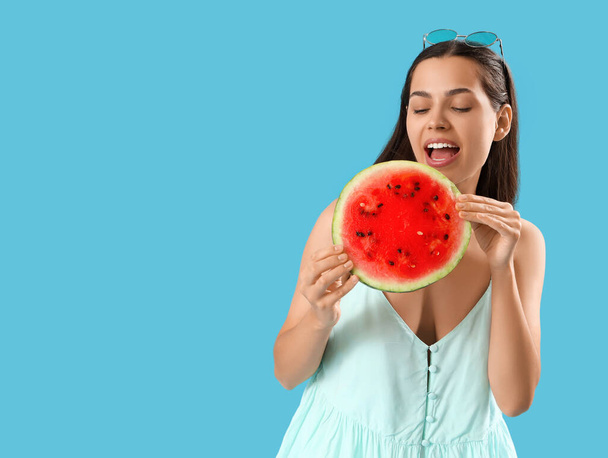 Красивая молодая женщина ест кусок свежего арбуза на синем фоне - Фото, изображение