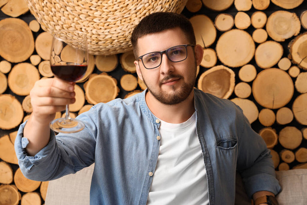 Νεαρό σομελιέ με ποτήρι κρασί σε ξύλινο φόντο - Φωτογραφία, εικόνα