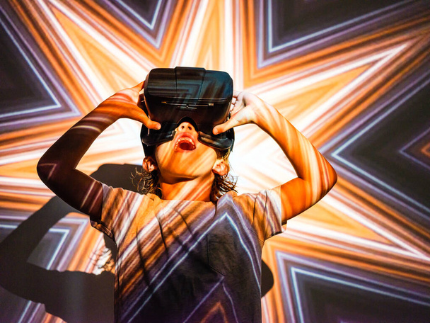 Низький кут здивованого маленького хлопчика, який вивчає віртуальну реальність, використовуючи окуляри VR та освітлені проектором із зображенням зірки - Фото, зображення