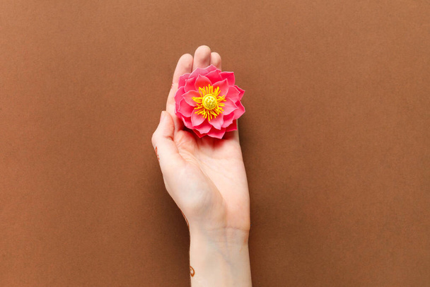 Жіноча рука з квіткою лотоса для святкування Діалі на коричневому фоні - Фото, зображення