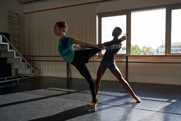 Couple of black boy and white girl in a class doing a training in ballet academy - Photo, Image