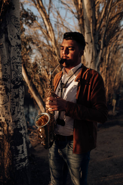 młody muzyk grający na saksofonie o zachodzie słońca - Zdjęcie, obraz