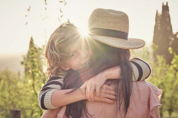 Vista trasera de la mujer en sombrero con estilo con hijo en el día de verano soleado - Foto, Imagen