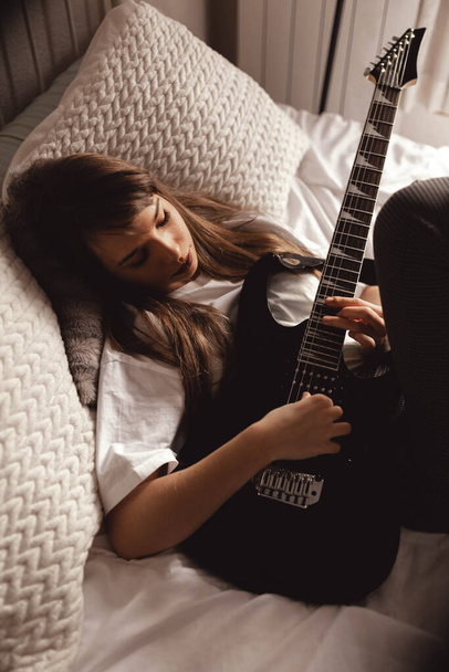 d'en haut Jeune femme brune jouant de la guitare sur le lit - Photo, image