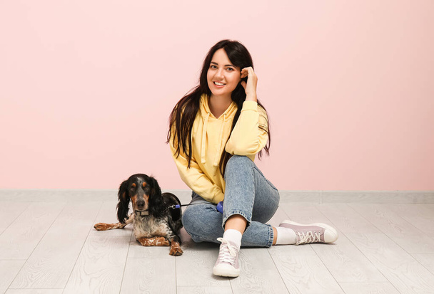Жіночий собачий обробник з домашнім улюбленцем, що сидить біля рожевої стіни - Фото, зображення