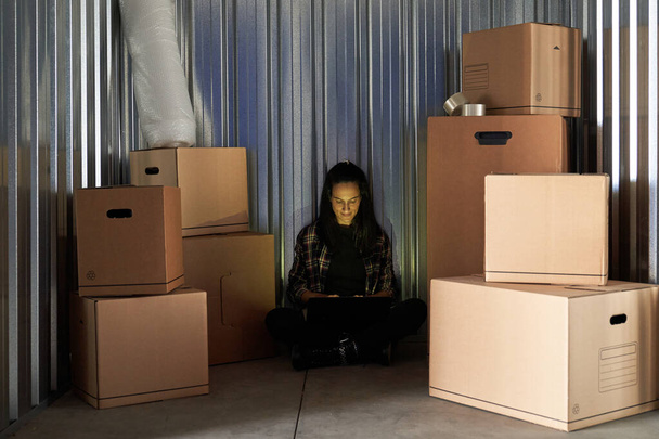 Nuori kaunis nainen varastossa tallentaa liikkuvat laatikot järjestämällä hänen kannettava tietokone - Valokuva, kuva