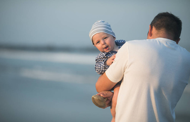 Feliz día de los padres. Padre y bebé juegan en la playa. Papá y él Niño juntos disfrutando de la puesta del sol. Amor padre soltero abraza lindo hijo pequeño. - Foto, Imagen