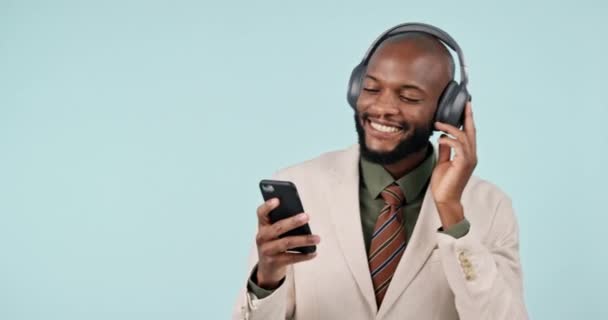 Geschäftsmann, telefonieren und tanzen mit Kopfhörern im Studio Internet, Energie und App. Glücklich, Smartphone und eine professionelle Person aus Kenia auf blauem Hintergrund hören oder Musik online streamen. - Filmmaterial, Video