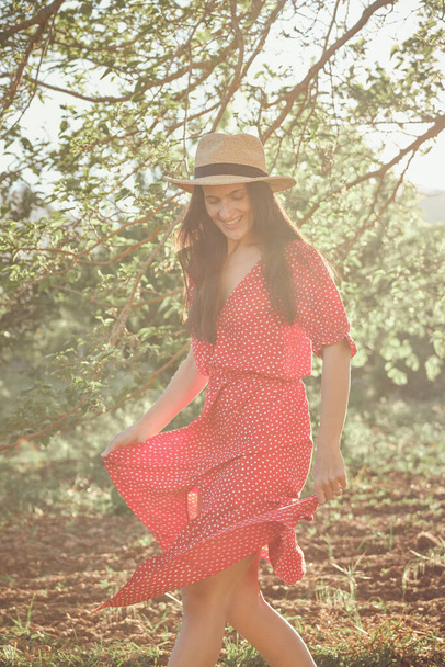 Dorosła kobieta w letniej sukience i kapeluszu w lesie w słoneczny dzień - Zdjęcie, obraz
