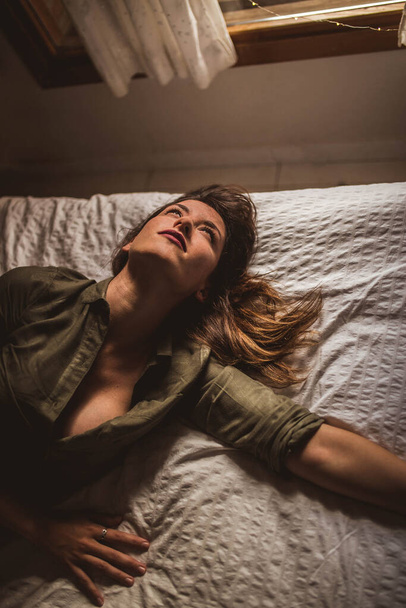 Kaunis nainen makaa sängyllä ja katselee ylös - Valokuva, kuva