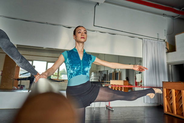 Χορεύτρια μπαλέτου ζεσταίνεται και χορεύει σε μια ακαδημία χορού - Φωτογραφία, εικόνα