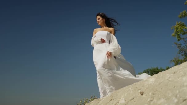Una chica con un vestido blanco está de pie sobre una roca. Una mujer mira a la distancia en la interminable superficie del mar - Metraje, vídeo