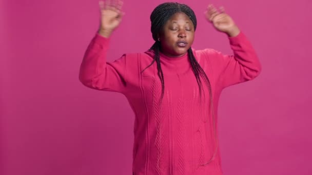 Молодая черная женщина недовольна и говорит "нет" в камеру с поднятыми руками. Африканский блогер моды разочаровавшись в самовыражении на розовом фоне. - Кадры, видео