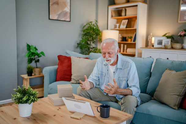 Jeden senior człowiek dziadek emeryt z siwymi włosami i brodą otrzymać prezenty w pudełku otwarte karty czytać szczęśliwy uśmiech przed laptopem komputera w domu o online wideo połączenie skopiować przestrzeń - Zdjęcie, obraz