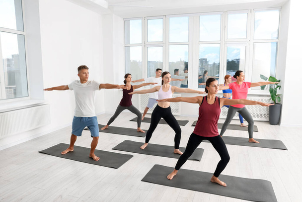 Group of people practicing yoga on mats indoors - Foto, afbeelding