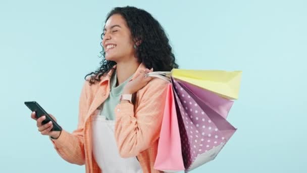 Phone, shopping bag or happy woman on social media to search for fashion deal, sales offer or online promo. Memes, blue background or excited customer with smile typing a discount code in studio. - Felvétel, videó
