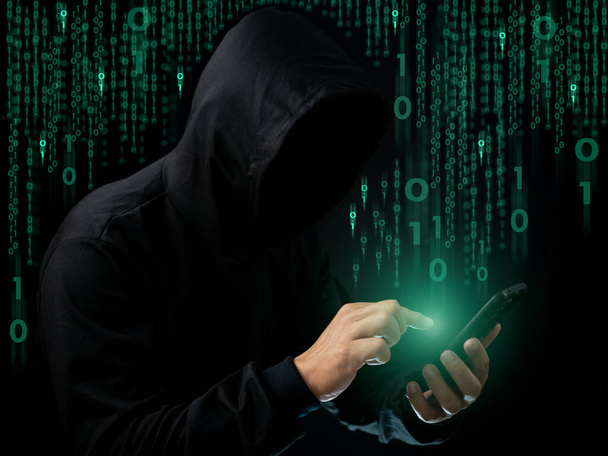 ハッカーは暗闇の中で電話をかけている. インターネットネットワークと情報スパイの情報セキュリティの概念. ウイルス攻撃。 ハッカー攻撃. - 写真・画像