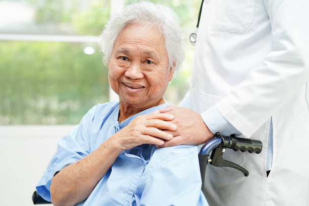Orvos segít ázsiai idős fogyatékos nő beteg gazdaság sétapálca ráncos kézzel a kórházban. - Fotó, kép